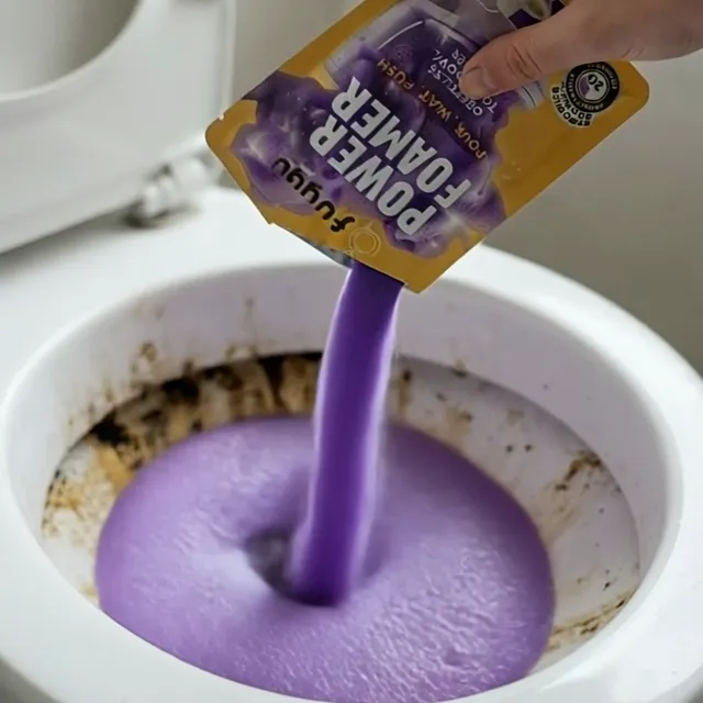 A hand pours a bag of Fuugu Aclass Virg into a toilet bowl with brown limescale, and purple foam rises into a thick dome